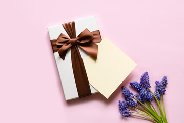 Flat lay composition with muscari flowers, gift box and envelope mockup with blank greeting card on light background. Minimal floral frame. Happy mother's day, women's day, birthday or wedding.