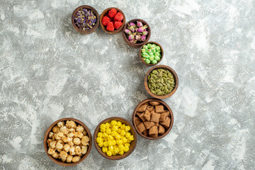 top view different candies with nuts and flowers on white background candy tea sugar cake many