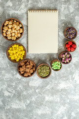 top view different candies with nuts and notepad on a white background candy tea sugar cake many