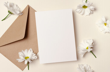 Blank greeting card mockup with envelope and white daisy flowers, top view with copy space