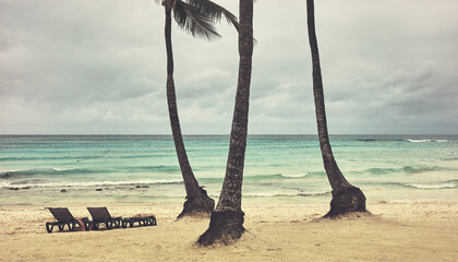 Tropical beach with cloudy sky, color toning applied.