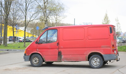 An old rusty red minibus is parked on the street, Bolshevikov Avenue, St. Petersburg, Russia, May 2023