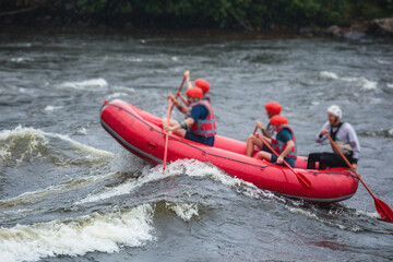 Red raft boat during whitewater rafting extreme water sports on water rapids, group of sportsmen in wetsuits kayaking and canoeing on the river, water sports team with a big splash of water