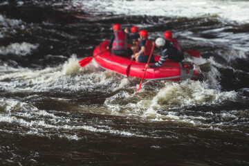 Red raft boat during whitewater rafting extreme water sports on water rapids, group of sportsmen in wetsuits kayaking and canoeing on the river, water sports team with a big splash of water
