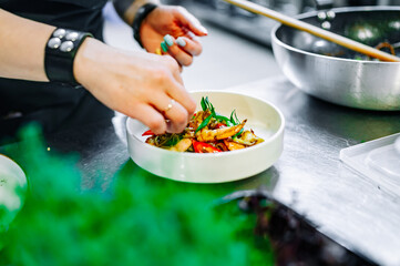 Chef cooking Stir fry noodles with vegetables and shrimps on restaurant kitchen