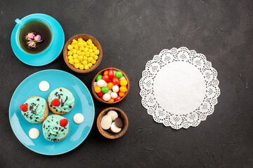 top view little creamy cakes with cup of tea and candies on the dark background tea cream cake biscuit dessert color