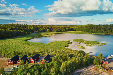 Aerial view of colorful boats near wooden berth and buildings in the countryside of Finland at sunset