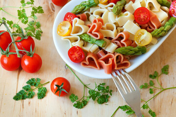 Romantic dinner. Delicious heart-shaped pasta with tomatoes, asparagus and fresh herbs