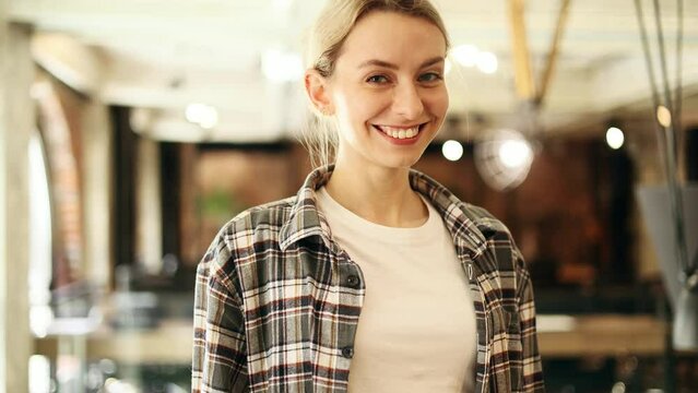 Portrait of charming blond woman freelancer in casual clothes and looking at the camera at coworking workplace Confident young trainee pensive thinking about future career indoors
