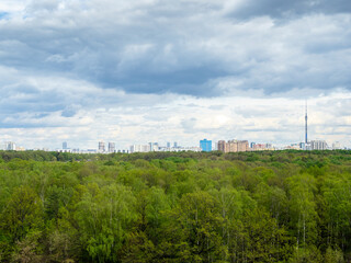 Fototapeta na wymiar gray rainy clouds over green forest and city on horizon on spring day