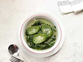 Sayur bening bayam dan gambas or clear soup of spinach and luffa vegetables. Serve in white ceramics bowl