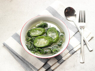 Sayur bening bayam dan gambas or clear soup of spinach and luffa vegetables. Serve in white ceramics bowl