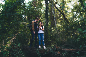 Naklejka na ściany i meble Happy couple standing on tree trunk in forest