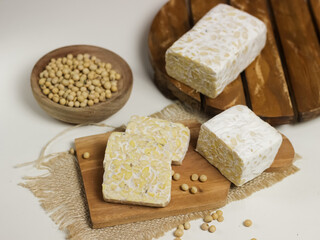 Raw Tempeh or Tempe. Tempeh Slices on Wooden White Background. Tempe Made From Fermented Soybeans