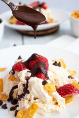 
Ice cream with strawberries and chocolate drizzle. On a wooden background. Dessert