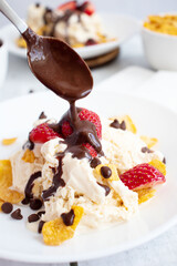 
Ice cream with strawberries and chocolate drizzle. On a wooden background. Dessert