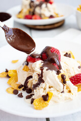 
Ice cream with strawberries and chocolate drizzle. On a wooden background. Dessert