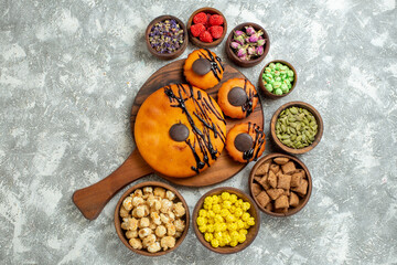 top view yummy cakes with chocolate icing and candies on white background cake cocoa biscuit pie dessert sweet cookie