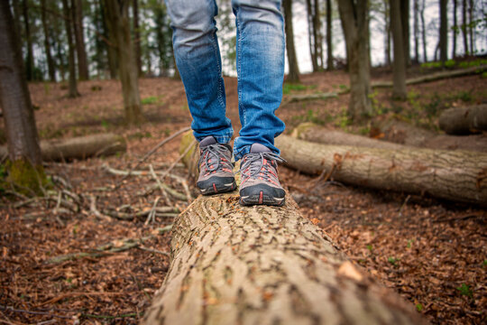 close up of a man walking along a log in the countryside.