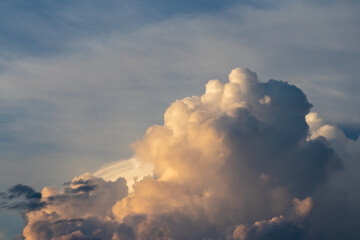 Puffy orange and white stormy cumulus clouds with blue sky