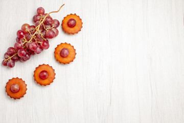 top view yummy little cakes with fresh grapes on white background dessert cookie biscuit tea cake pie