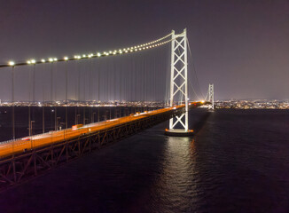 Lights from traffic blur over long suspension bridge lit at night