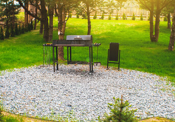Modern iron grill. Place for barbecue outdoors near the house. Fire with wood. Summer time for...