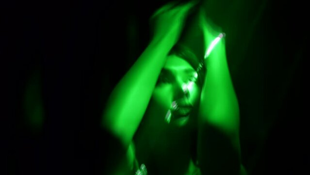 sexy brunette woman dancing in darkness with enigmatic green light, portrait of lady in nightclub