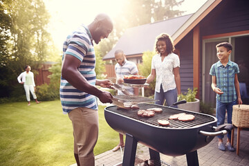 A happy African American family from the United States grilling meat in their backyard while celebrating Independence Day, July 4th