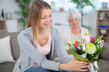 young daughter and mother with bouquet of flowers at home