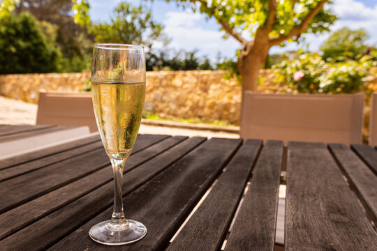 a glass of cava on a brown table, with a blurred background