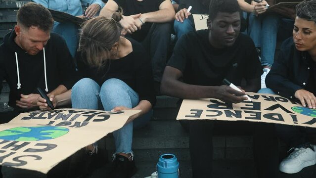 Multiracial activists designing protest banners against climate change - Global warming concept