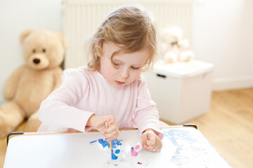 Three-Year-Old Girl Enthusiastically Painting with Brushes and Paints