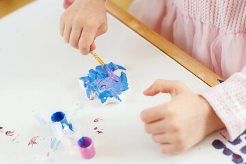 Child's Hands Painting with Colorful Brushes