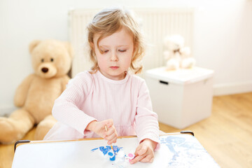 Young Artist at Work: Three-Year-Old Girl Painting with Joy and Enthusiasm