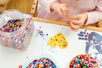 Top-View Close-Up of a Little Girl Playing with Colorful Beads: Developing Motor Skills and Creativity through Play