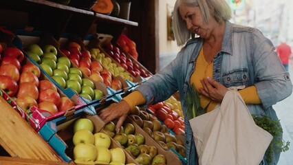 Happy senior woman buying fresh fruits at the market - Shopping food concept
