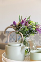 Detail of a teapot with two cups ready pra breakfast. There is a bouquet of fresh flowers.