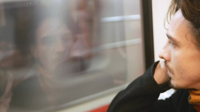 lonely pensive man in subway looks out window, an underground train, flow of life, time passes, slow motion.