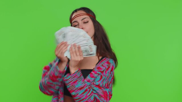 Rich pleased boss young woman waving money dollar cash banknotes bills like a fan, success business career, lottery winner, big income, wealth. Hippie girl isolated on green chroma key background