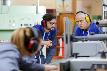 apprentice asking senior worker a question in factory
