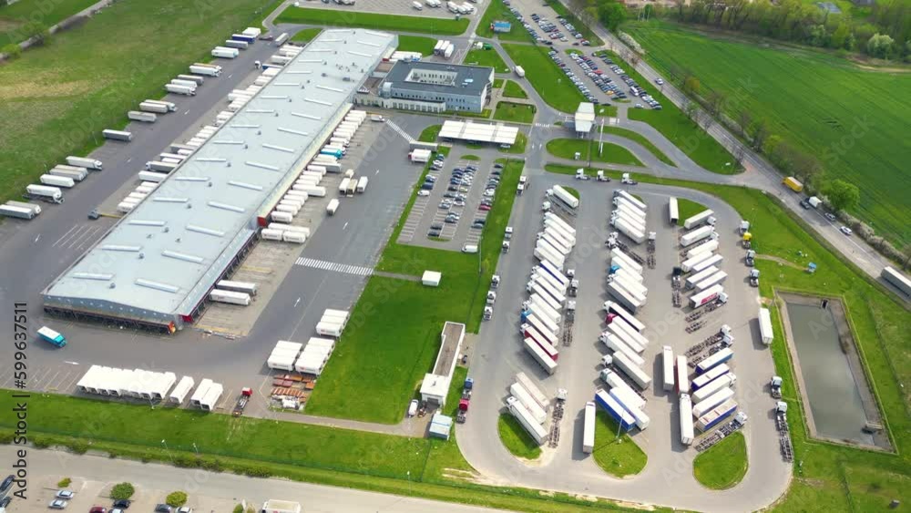 Wall mural Aerial shot of industrial warehouse. Loading hub and many trucks with cargo trailers. Aerial view of goods warehouse. Modern Distribution Center from outside. Aerial view of warehouse with trucks. - Wall murals