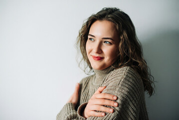 Romantic wife eagerly anticipating husband's return, standing by window with arms wrapped around...