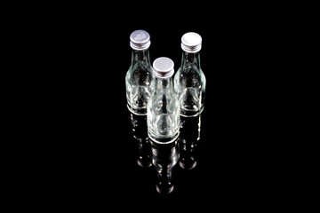 detailed view of small glass bottles on black table with black background