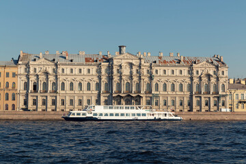 Fototapeta na wymiar A view from a river on facades of buildings by sunny summer day. View of Saint Petersburg. A boat and an embankment in front.