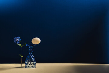 Abstract composition with a flower and an inverted blue glass and a white stone