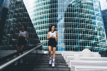 Optimistic sportswoman warming up on stairs