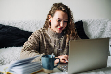 Student video chatting with friends, taking a break from studying at home. Young woman in...