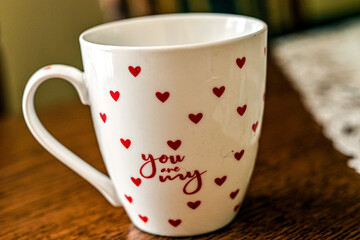 white mug of red tea and hearts on wooden table