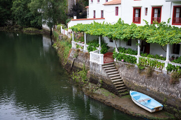 Fototapeta na wymiar Una bella casa con embarcadero a orillas de un río con una terraza y su parra en Galicia, España.